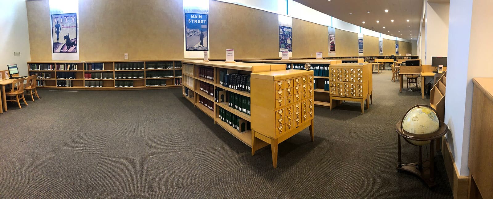 Sala di lettura della biblioteca con scaffali bassi e schedari in legno