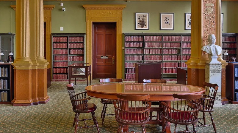 Sala della biblioteca con un grande tavolo rotondo, sedie in legno e scaffali di libri