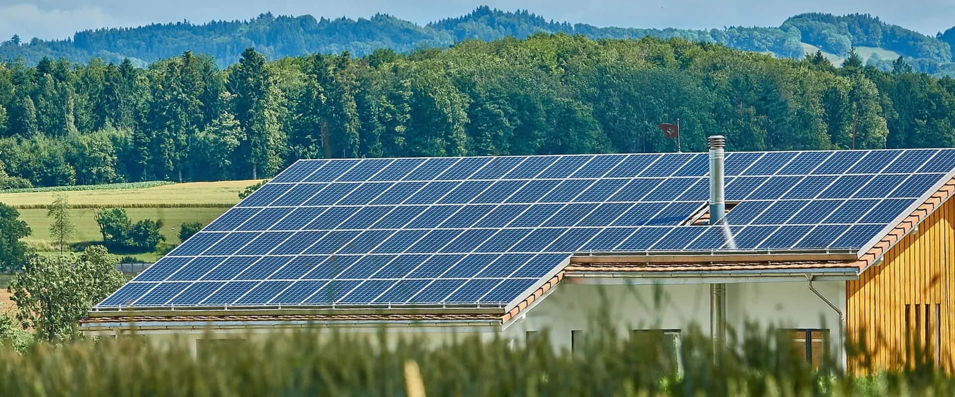 Pannelli fotovoltaici sul tetto di un edificio pubblico, con le colline sullo sfondo