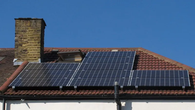 Pannelli fotovoltaici sul tetto spiovente di un edificio, accanto al comignolo
