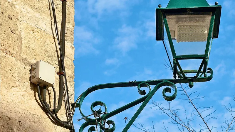 Lampione in ferro battuto con lampada a LED su un muro in pietra