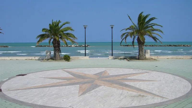 Piazzetta sul lungomare con la rosa dei venti disegnata sul pavimento e due palme