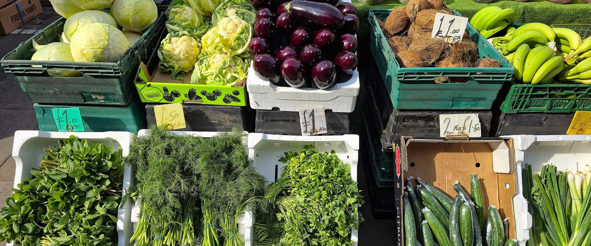 Banco del mercato con cassette di verdura fresca: cavoli, melanzane, peperoni e insalate