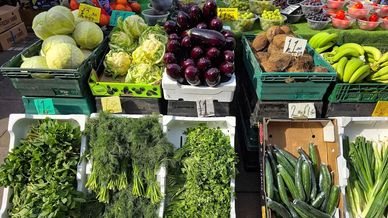 Banco del mercato con cassette di verdura fresca: cavoli, melanzane, peperoni e insalate