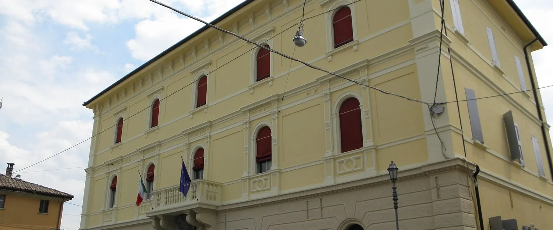 Facciata gialla del palazzo municipale con le bandiere al balcone
