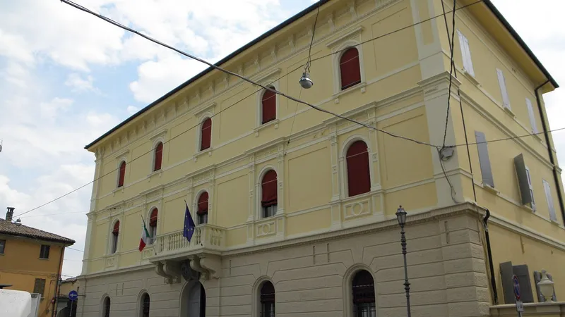 Facciata gialla del palazzo municipale con le bandiere al balcone