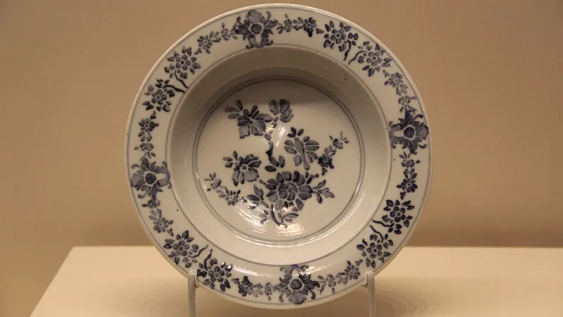 Piatto in ceramica bianca decorato con fiori blu, esposto in una vetrina