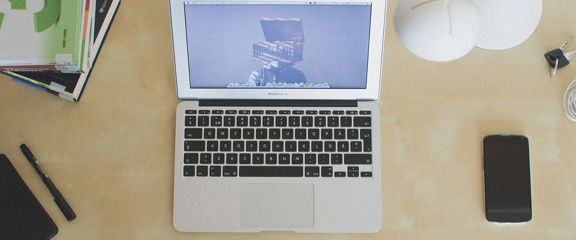 Computer portatile su una scrivania vista dall’alto, con un telefono e una tazza