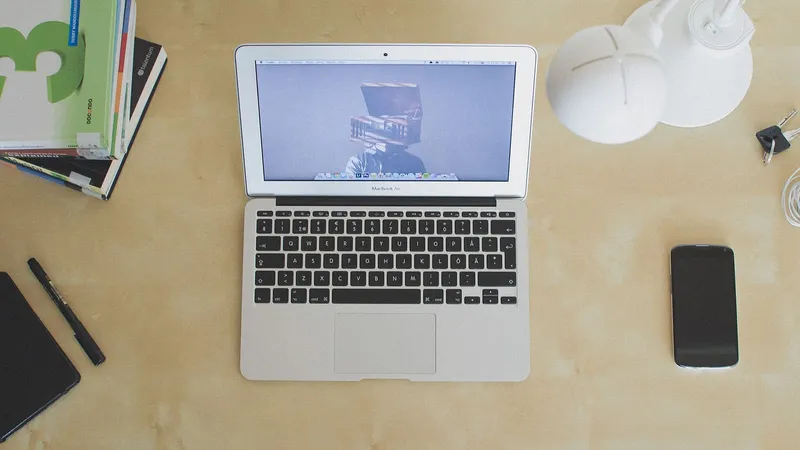 Computer portatile su una scrivania vista dall’alto, con un telefono e una tazza