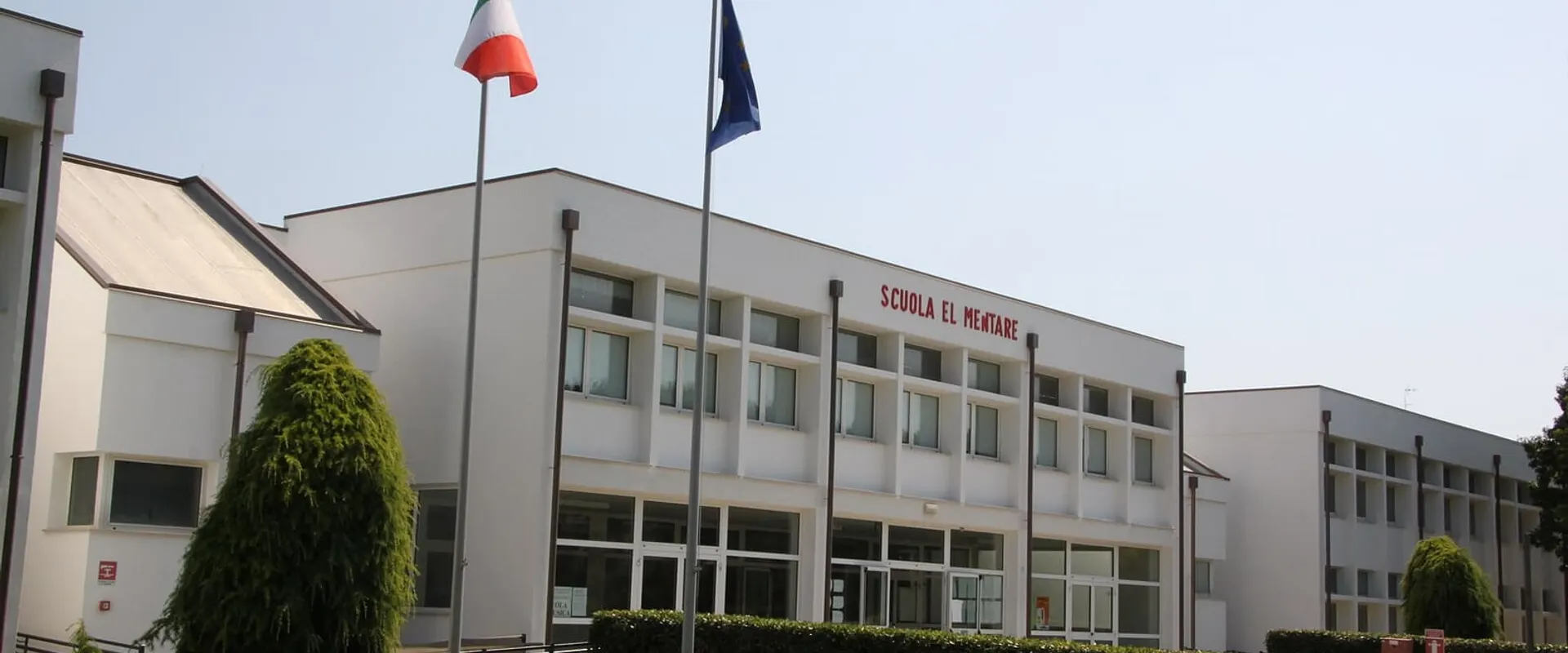 Edificio scolastico moderno a due piani con le bandiere davanti all’ingresso
