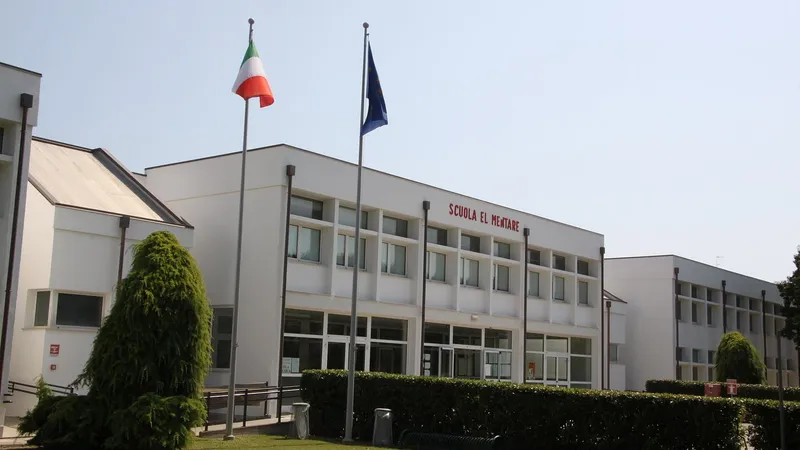 Edificio scolastico moderno a due piani con le bandiere davanti all’ingresso
