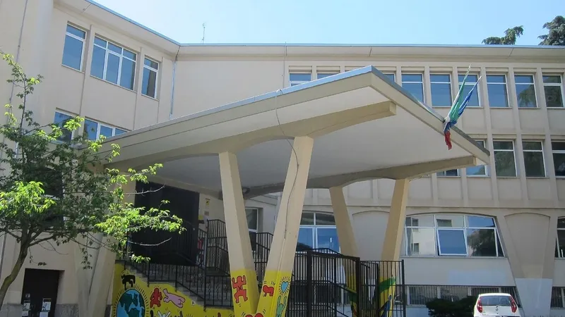 Ingresso della scuola con la pensilina e un murale colorato sul muro di cinta