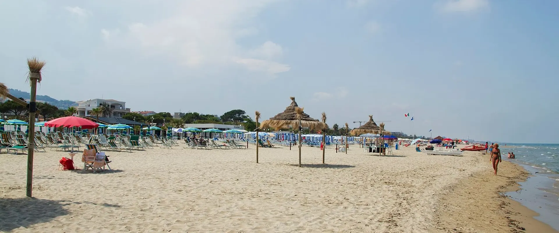 Spiaggia di sabbia con ombrelloni colorati e il mare calmo