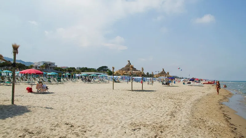 Spiaggia di sabbia con ombrelloni colorati e il mare calmo