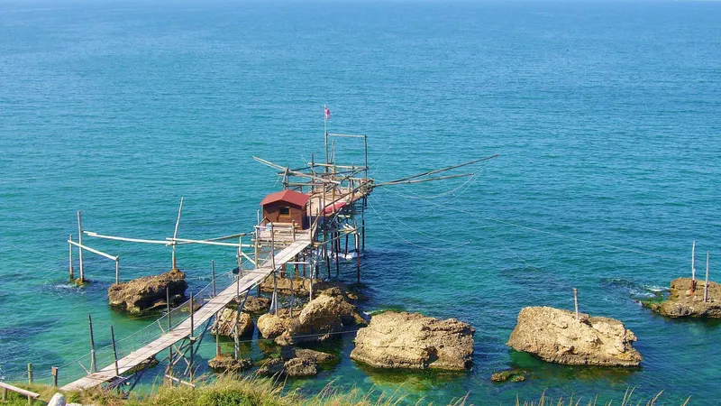 Trabocco in legno su palafitte sopra il mare turchese, collegato agli scogli da una passerella
