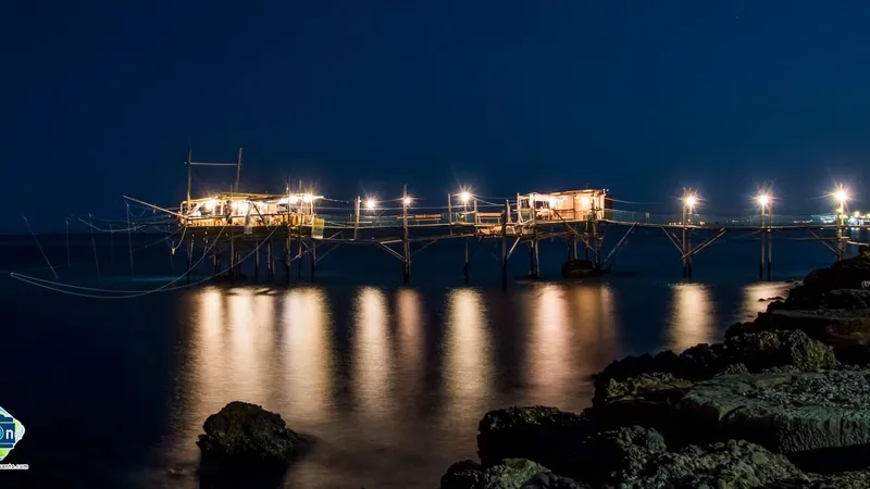 Il trabocco illuminato di notte, con le luci che si riflettono sul mare