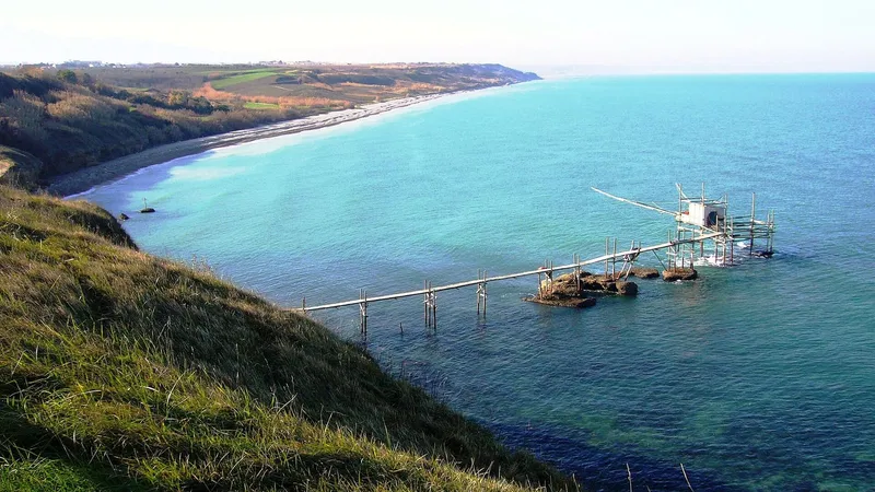 Trabocco sul mare visto dalla scogliera, con la spiaggia e il promontorio sullo sfondo