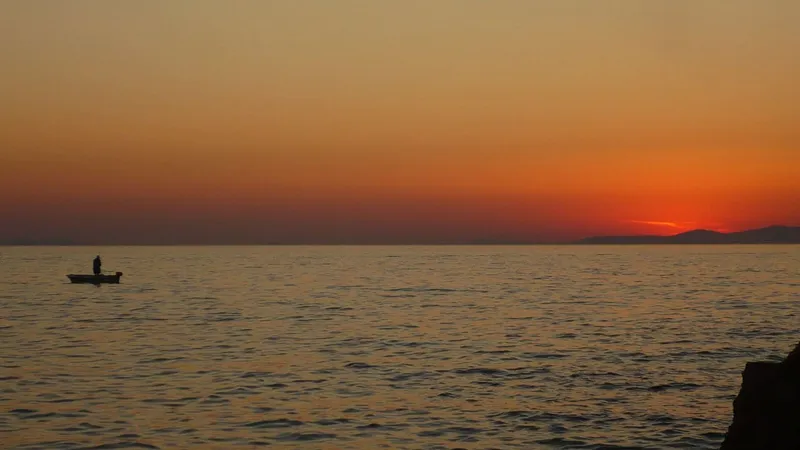 Tramonto sul mare con una piccola barca all’orizzonte