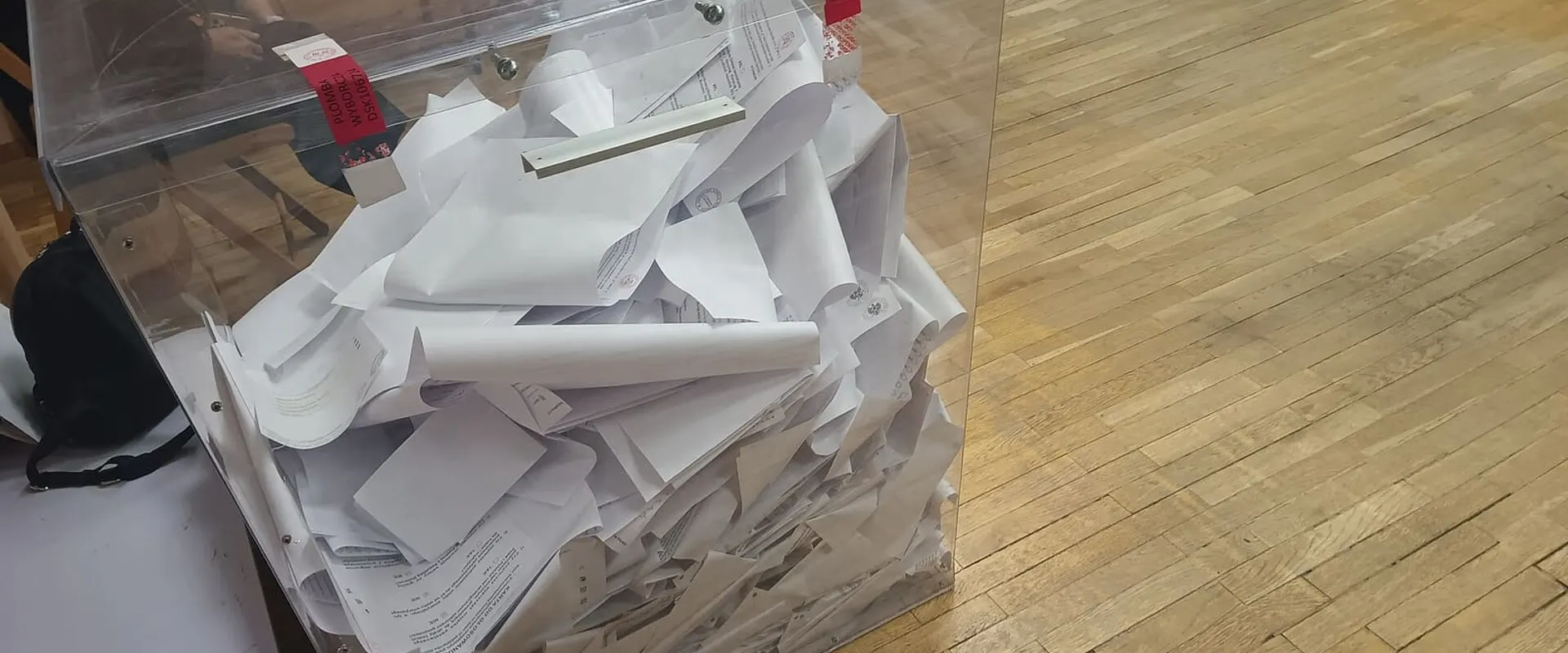 Urna trasparente piena di schede elettorali piegate