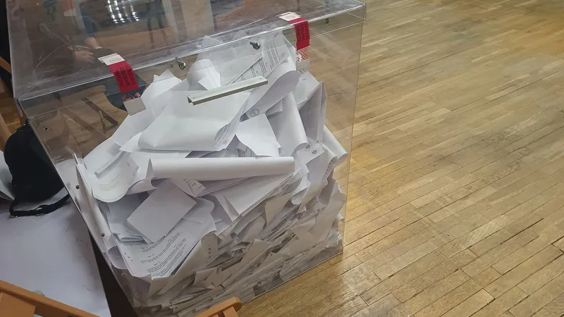Urna trasparente piena di schede elettorali piegate
