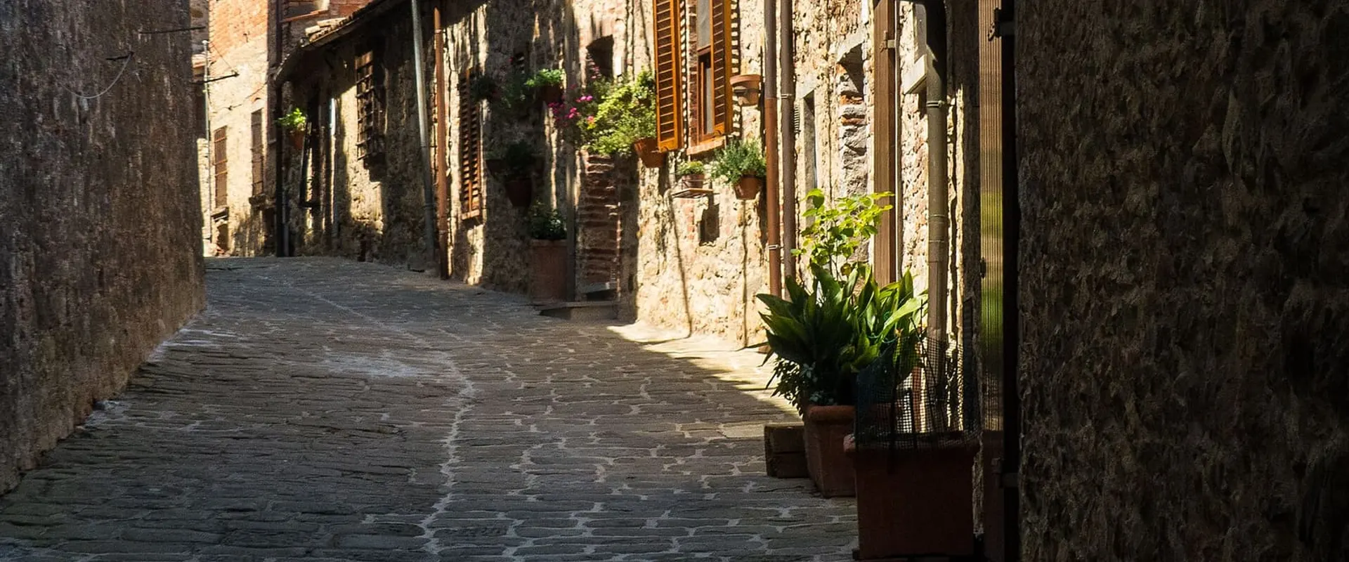 Vicolo lastricato in pietra del centro storico, con vasi di piante davanti alle case